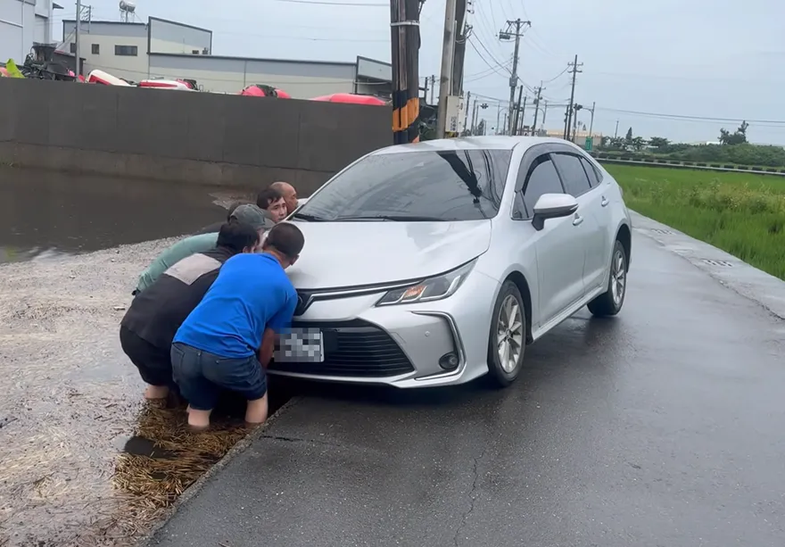 影/有你真好！伸港淹水「轎車陷水田」　工廠老闆率移工抬車